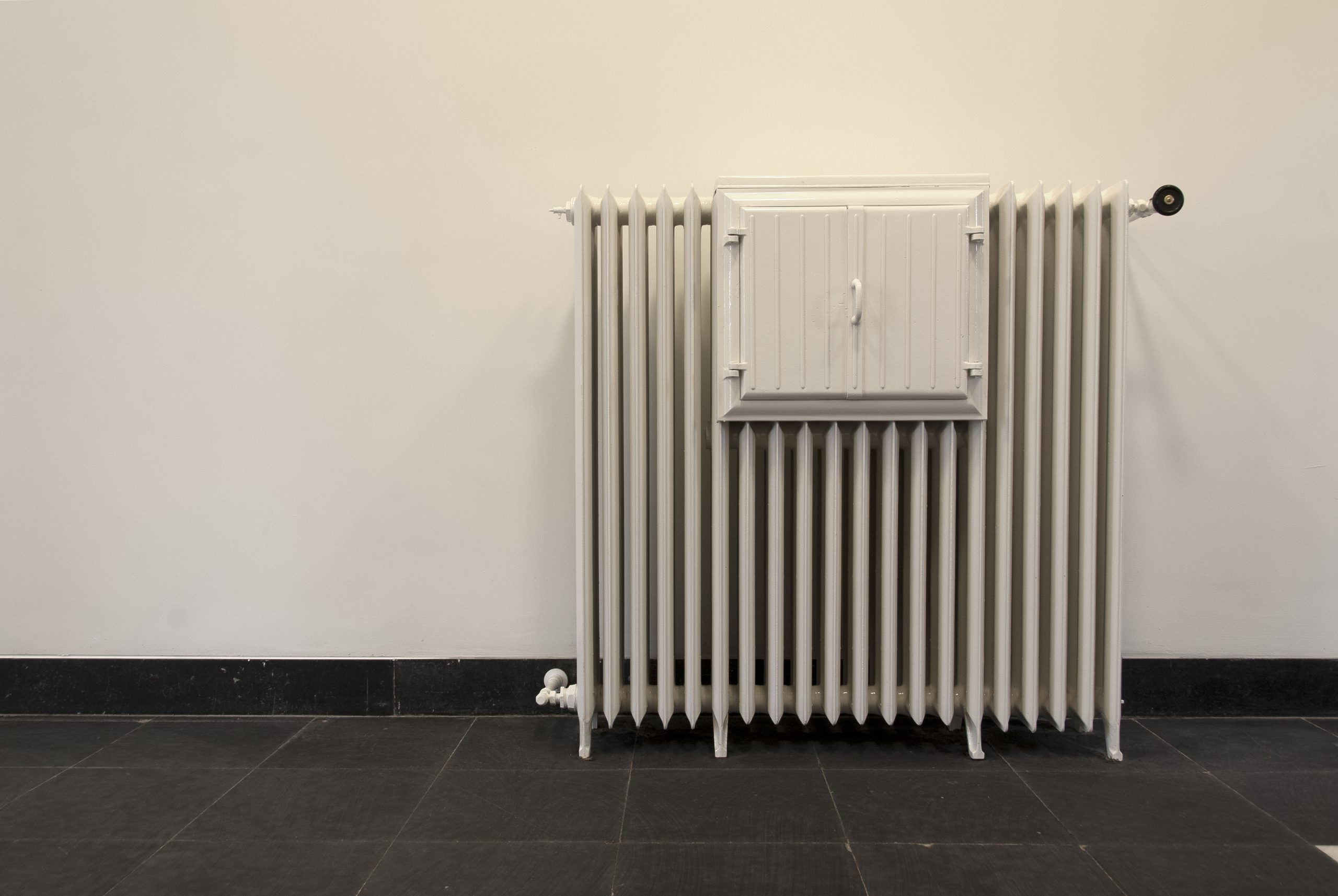 Bewaard gebleven gietijzeren radiator uit de keuken van het klooster met de originelen warmhoudkastjes.